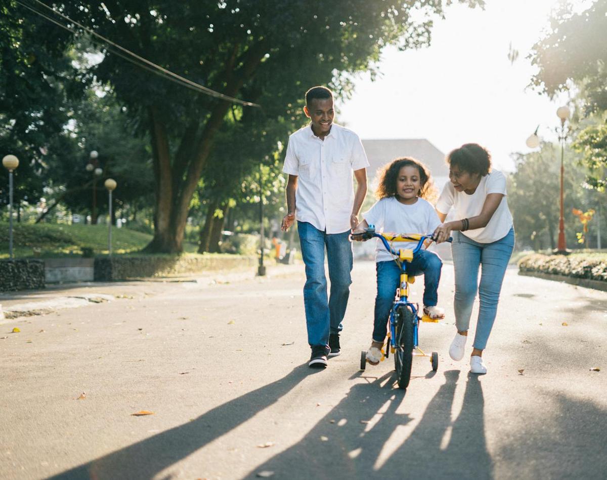Parents teaching their daughter to ride a bike