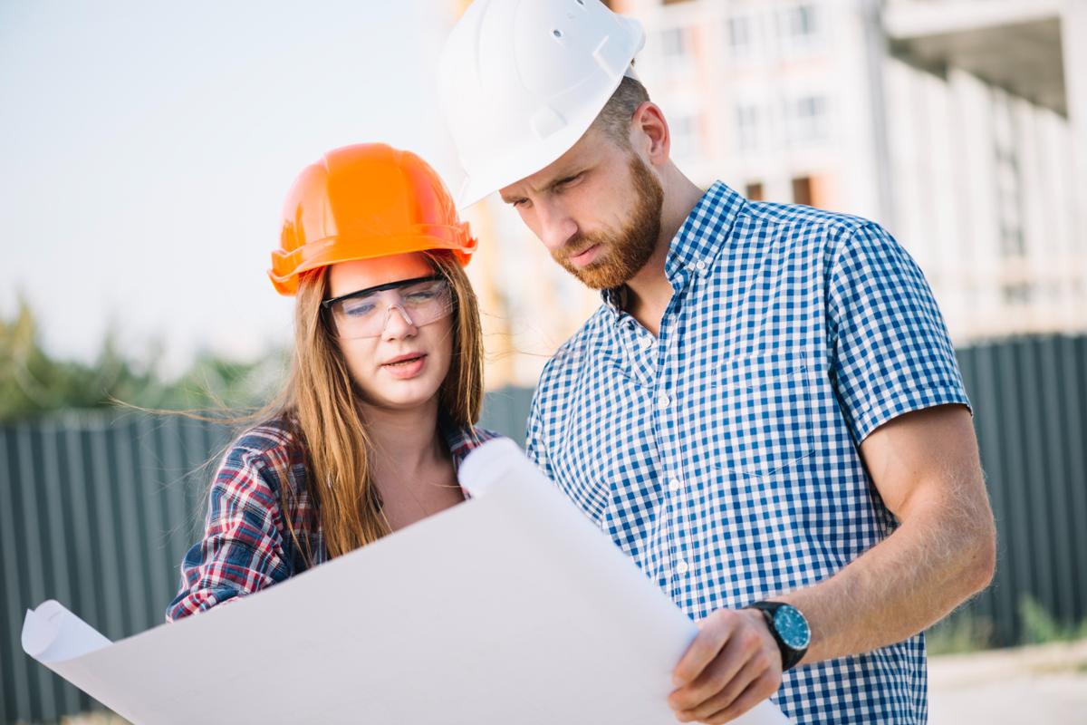 Man and woman wearing construction helmets looking at a blueprint