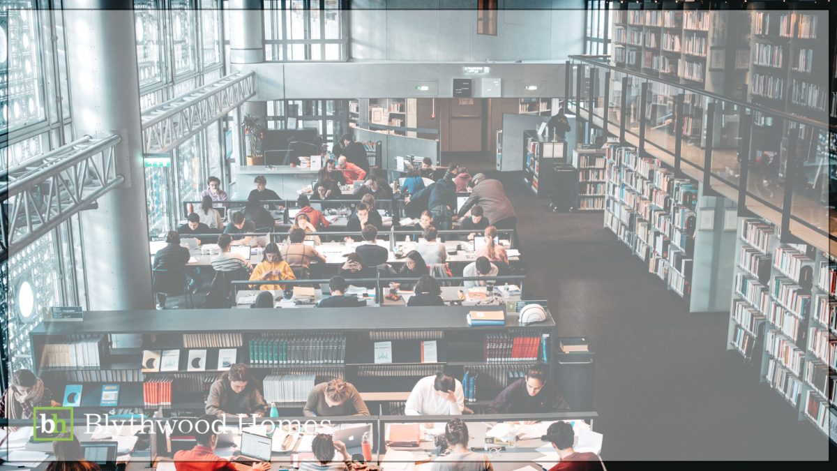 University students studying in a bright, modern library filled with bookshelves and natural light—illustrating the strong educational environment that makes Niagara an appealing region for young professionals and families, promoted by Blythwood Homes.